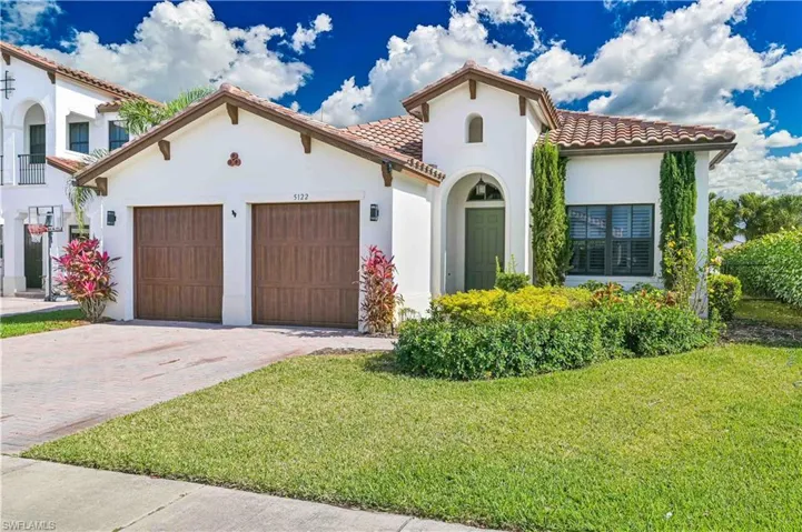 Mediterranean / spanish home with stucco siding, a tile roof, decorative driveway, a garage, and a front lawn