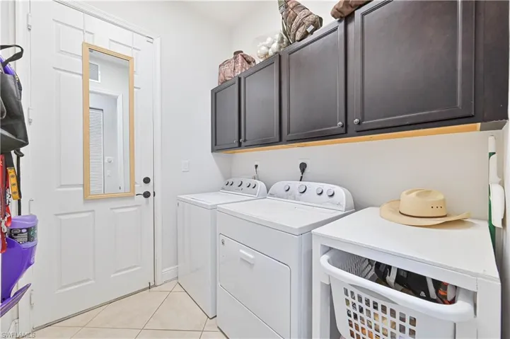 Laundry room with cabinet space, independent washer and dryer, and light tile patterned flooring