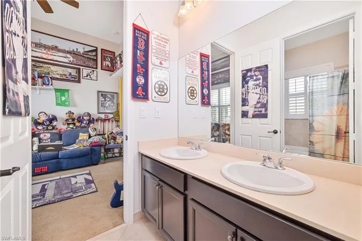 Bathroom featuring double vanity, light colored carpet, a shower with shower curtain, and a ceiling fan
