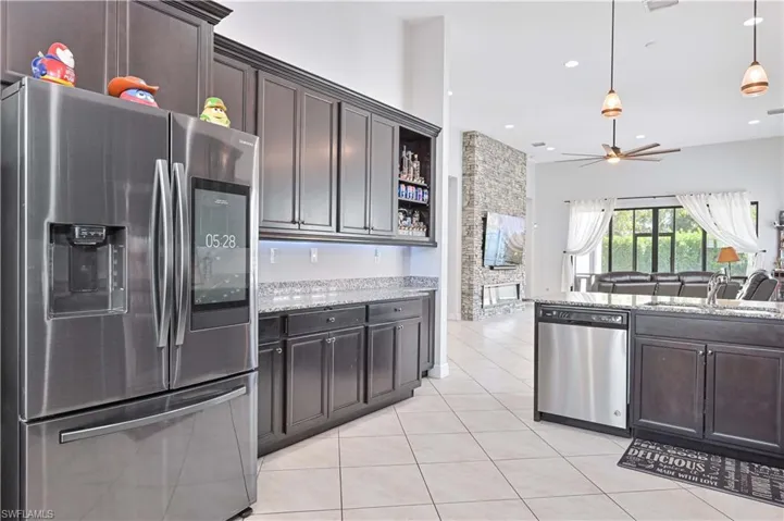 Kitchen featuring stainless steel appliances, open shelves, light tile patterned flooring, and dark wood finish cabinetry