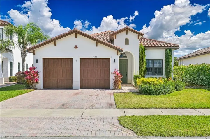 Mediterranean / spanish house with stucco siding, a garage, a front lawn, decorative driveway, and a tile roof