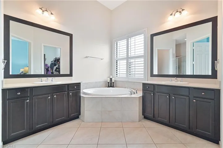 Full bathroom with a shower stall, light tile patterned floors, and two vanities