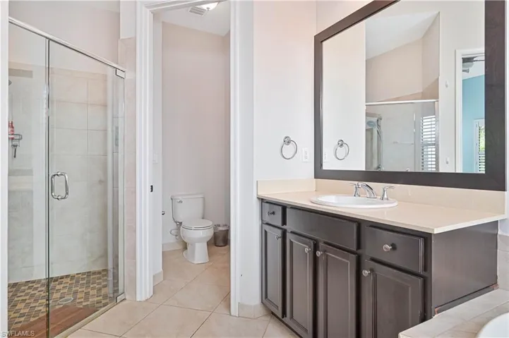 Full bath featuring a stall shower, vanity, and light tile patterned floors