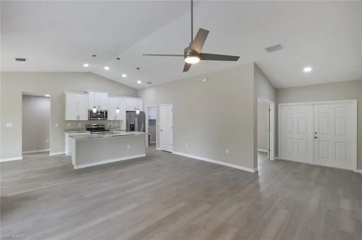 Unfurnished living room with high vaulted ceiling, ceiling fan, hardwood / wood-style floors, and sink