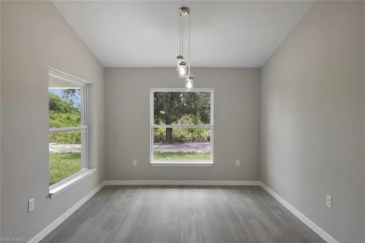 Empty room with a wealth of natural light, vaulted ceiling, and hardwood / wood-style flooring