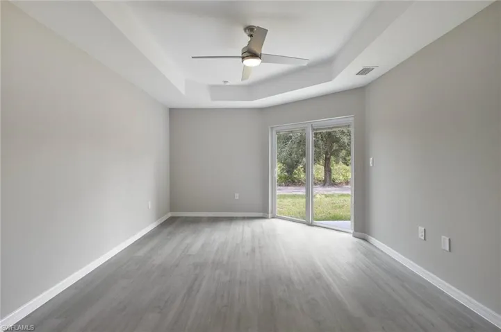 Unfurnished room with a tray ceiling, hardwood / wood-style flooring, and ceiling fan