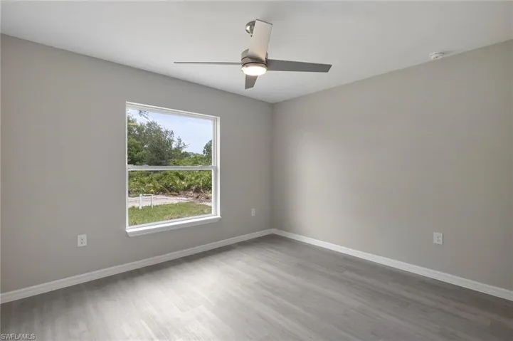 Empty room featuring a healthy amount of sunlight, ceiling fan, and hardwood / wood-style flooring