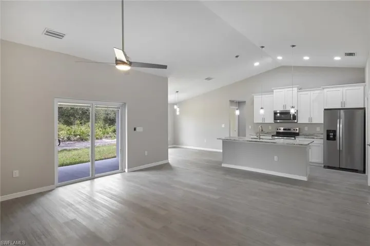 Kitchen featuring a center island with sink, stainless steel appliances, hardwood / wood-style flooring, white cabinets, and ceiling fan