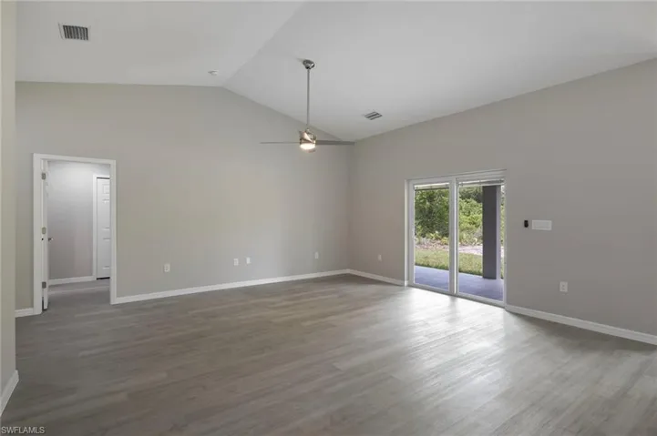 Empty room with high vaulted ceiling, hardwood / wood-style floors, and ceiling fan