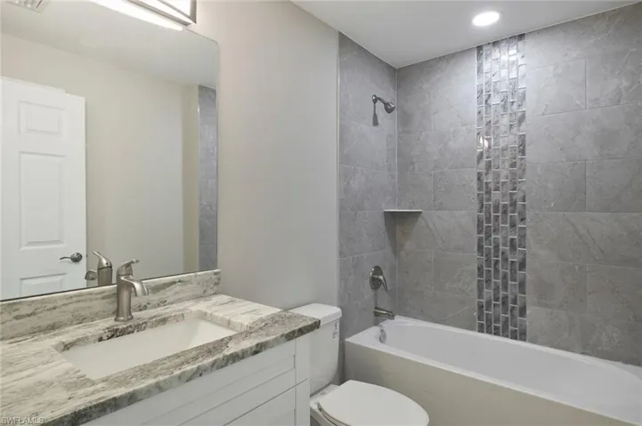 Full bathroom with vanity, toilet, and tiled shower / bath combo