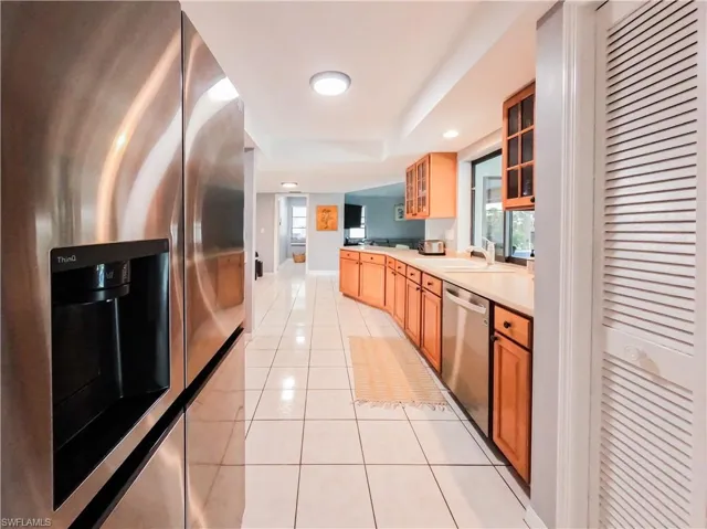 Kitchen with stainless steel appliances, sink, and light tile patterned floors