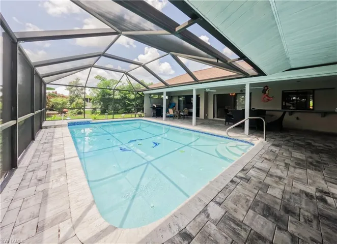 View of pool with a lanai, a patio area, and ceiling fan