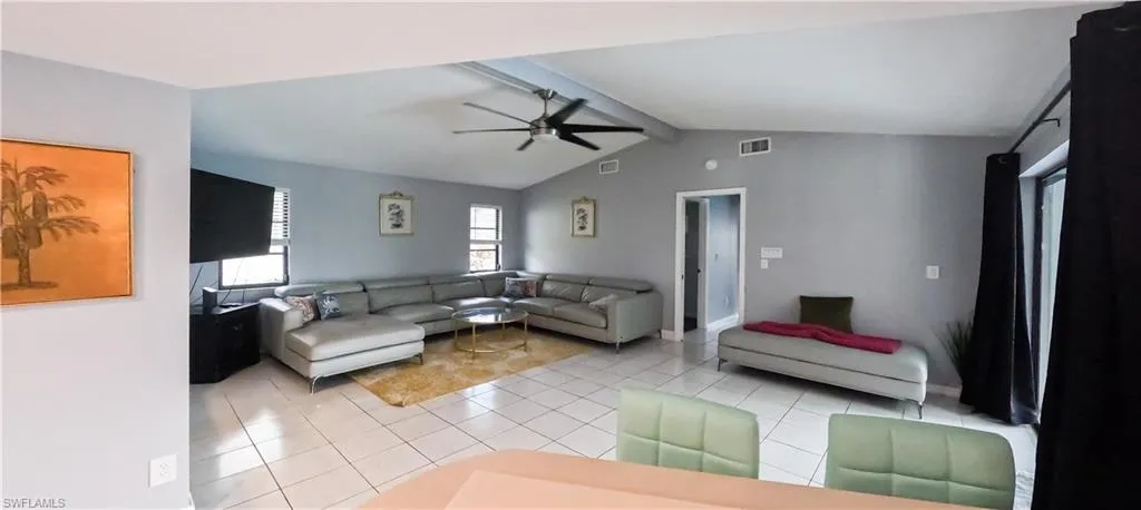 Living room featuring lofted ceiling with beams, light tile patterned floors, and ceiling fan