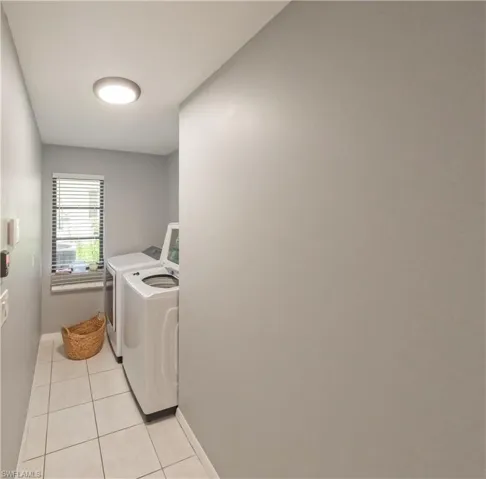 Clothes washing area with light tile patterned flooring and washing machine and clothes dryer