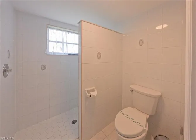 Bathroom with tile walls, toilet, and a tile shower