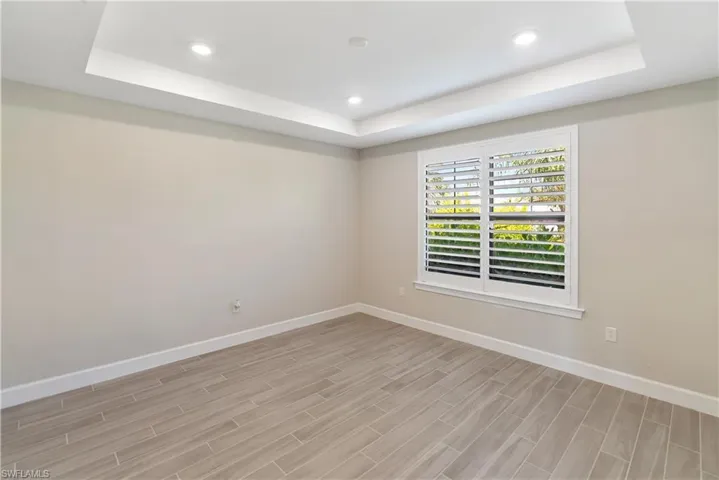 Bedroom/ Flex area with a raised ceiling, recessed lighting, french doors, wood tiled floors, and a closet