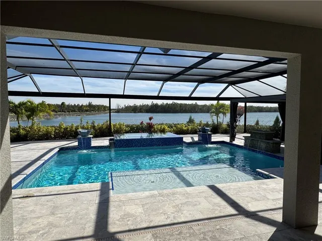 Integrated pool / spa featuring a screen enclosure and a lake view