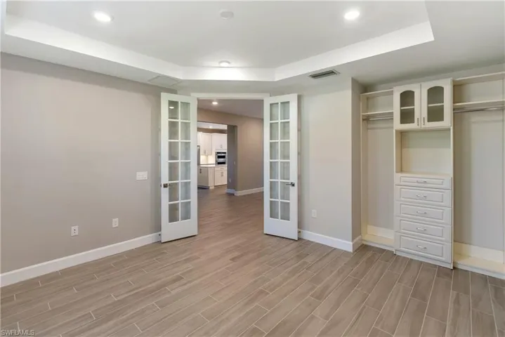 Bedroom/ Flex area with a raised ceiling, recessed lighting, french doors, wood tiled floors, and a closet