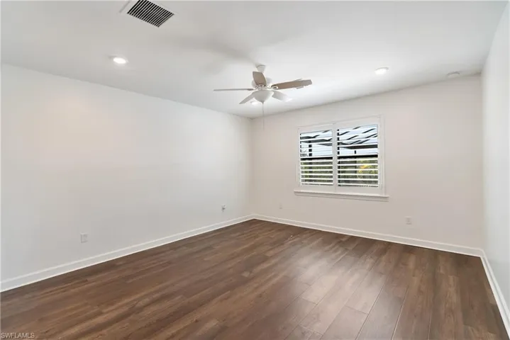 Primary bedroom with dark wood-style LVP floors, a ceiling fan, and recessed lighting