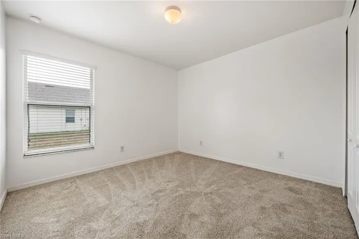 Unfurnished room with light colored carpet and baseboards