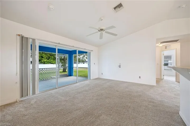 Unfurnished room featuring lofted ceiling, light carpet, and a ceiling fan
