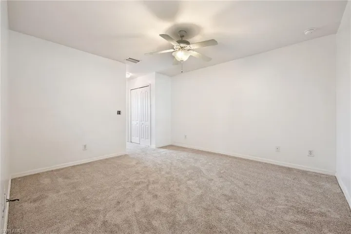 Empty room with ceiling fan and light carpet