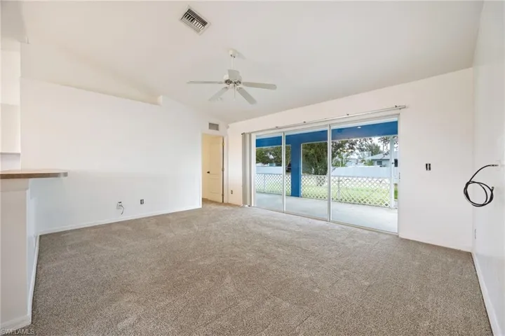 Unfurnished living room with vaulted ceiling, carpet floors, and ceiling fan