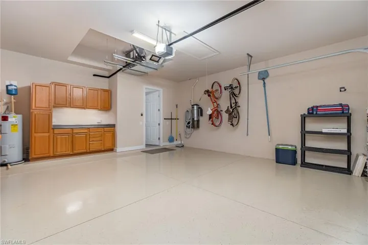 Garage featuring electric water heater and a garage door opener