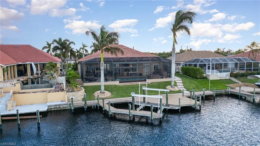 View of dock featuring a lawn, glass enclosure, a water view, and a pool