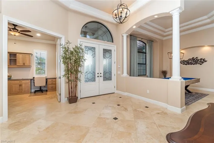 Foyer entrance featuring ornamental molding, built in desk, a high ceiling, and decorative columns