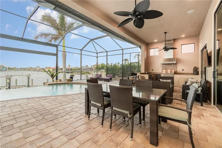 View of patio featuring a lanai, a water view, ceiling fan, and area for grilling