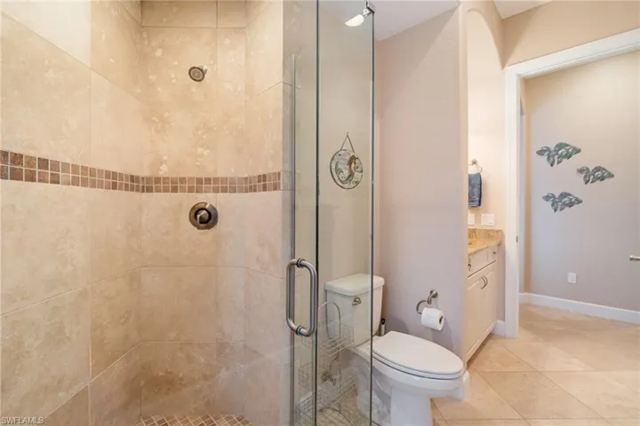 Bathroom with walk in shower, tile patterned floors, vanity, and toilet