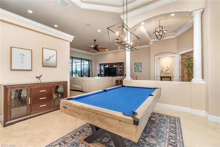 Rec room with ceiling fan with notable chandelier, ornate columns, billiards, and crown molding