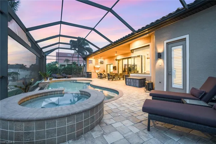 Pool at dusk with a patio, a lanai, and an in ground hot tub