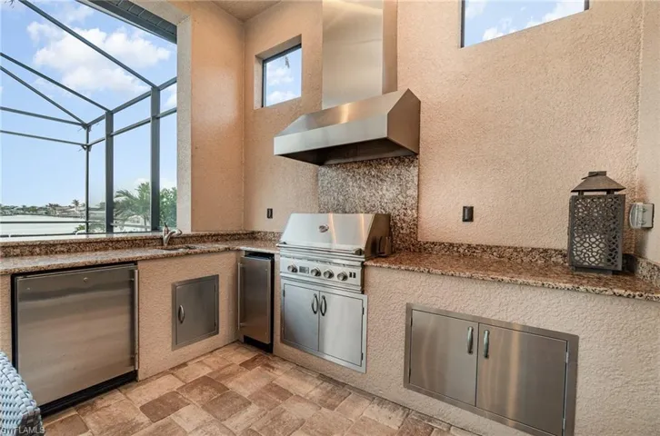 View of patio featuring grilling area, sink, a lanai, and an outdoor kitchen
