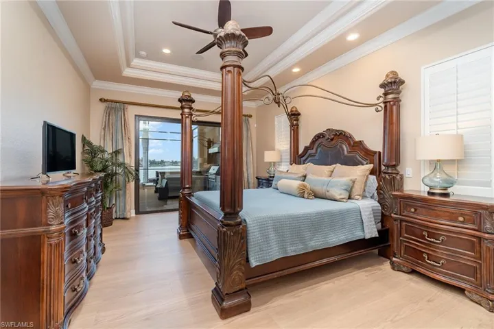 Bedroom with a tray ceiling, light hardwood / wood-style floors, ceiling fan, and crown molding