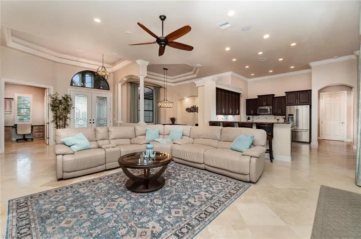 Living room with a high ceiling, ceiling fan, french doors, and ornamental molding