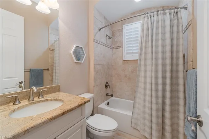 Full bathroom with vanity, shower / bath combo with shower curtain, and toilet