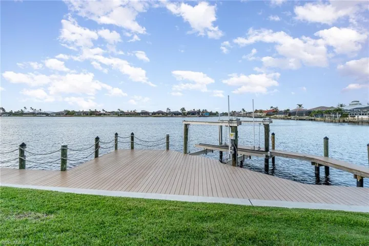 View of dock with a water view and a lawn
