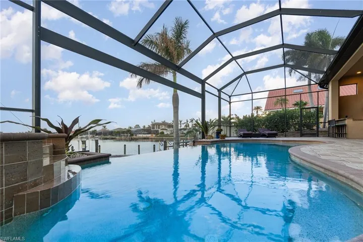 View of swimming pool with a lanai, a water view, and a patio area