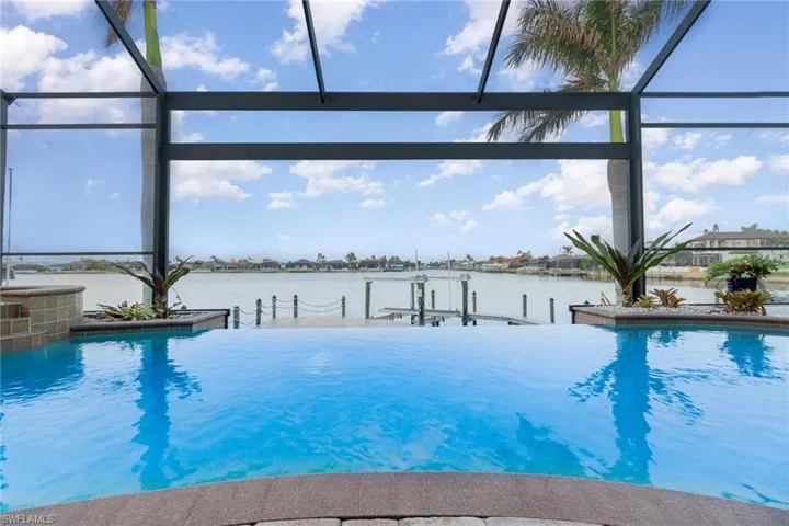 View of pool featuring a water view, glass enclosure, and a dock