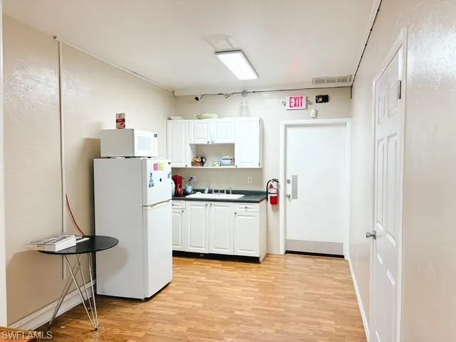 Kitchen featuring dark countertops, white appliances, white cabinetry, and open shelves