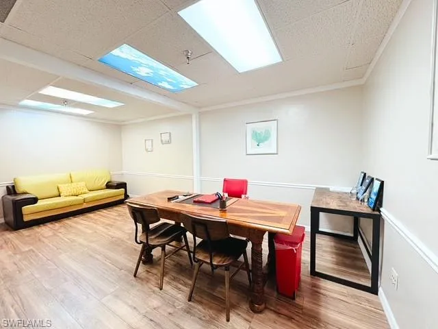 Dining area with light wood-style flooring, ornamental molding, and a drop ceiling
