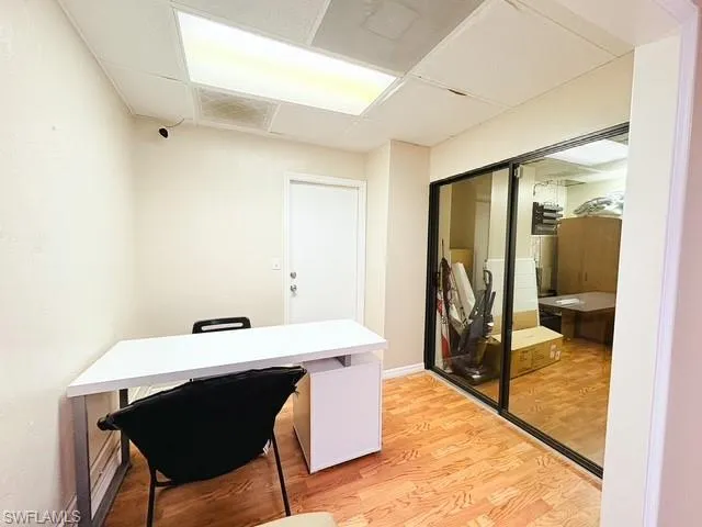 Office area with light wood-style flooring and a drop ceiling
