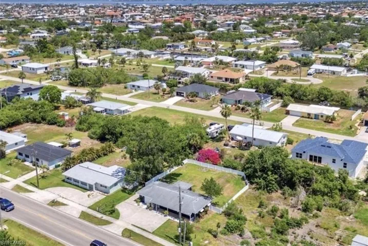 Aerial perspective of a residence featuring a covered front porch, concrete driveway, and a fenced backyard