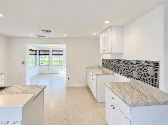 Kitchen featuring white cabinetry, stone-finish countertops, decorative tile backsplash, recessed lighting, and tile flooring