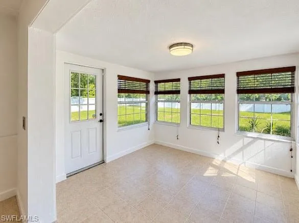 Sunroom featuring ceramic tile flooring, neutral walls, multiple windows with grid mullions, and a flush-mount circular ceiling fixture