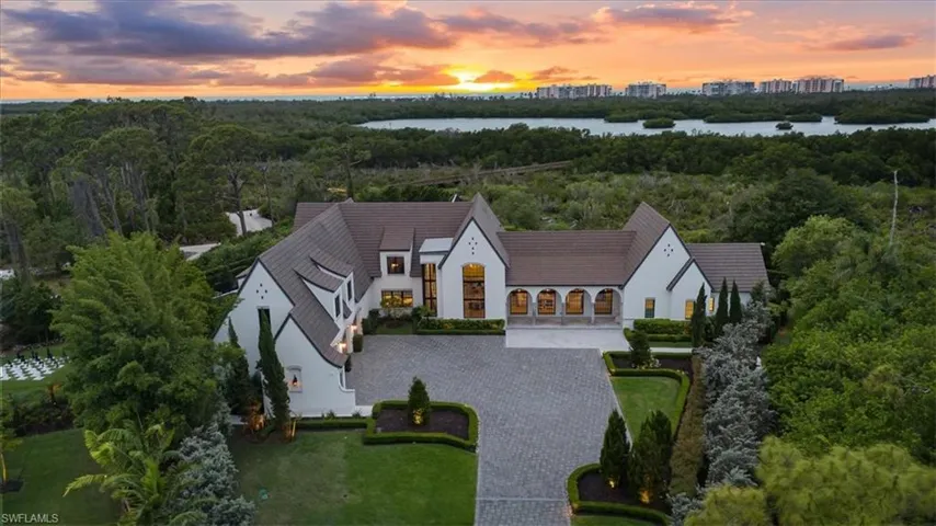 Aerial view at dusk featuring a water view and a wooded view