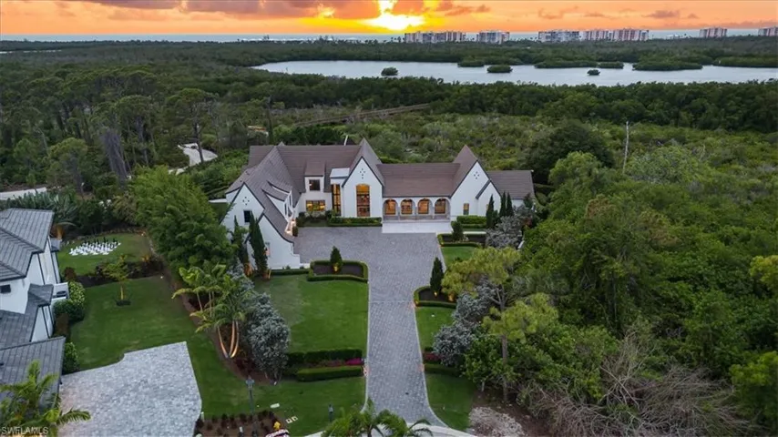 Aerial view at dusk with a water view and a view of trees
