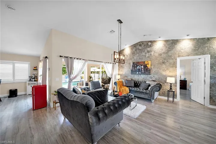 Living area with lofted ceiling, a chandelier, and light wood-type flooring